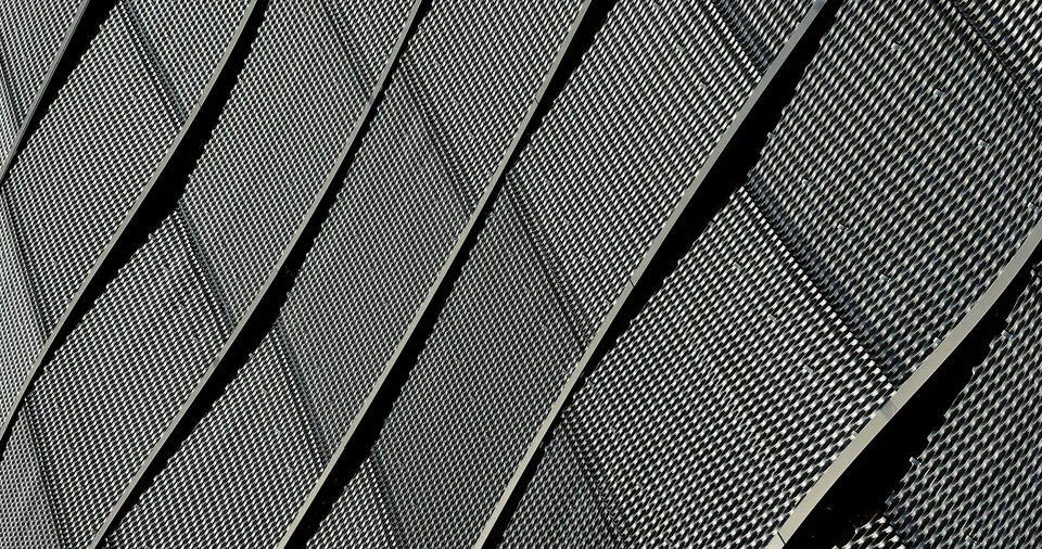 Close view of curved perforated metal facade panels with staggered vertical joints