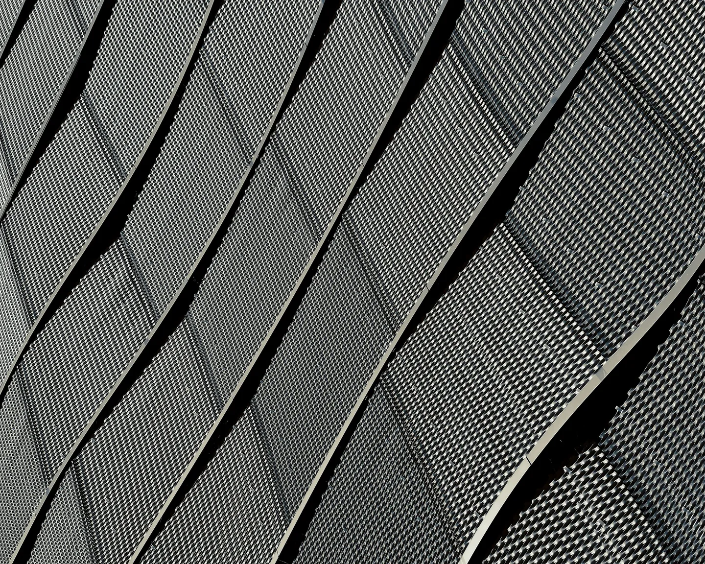 Close view of curved perforated metal facade panels with staggered vertical joints