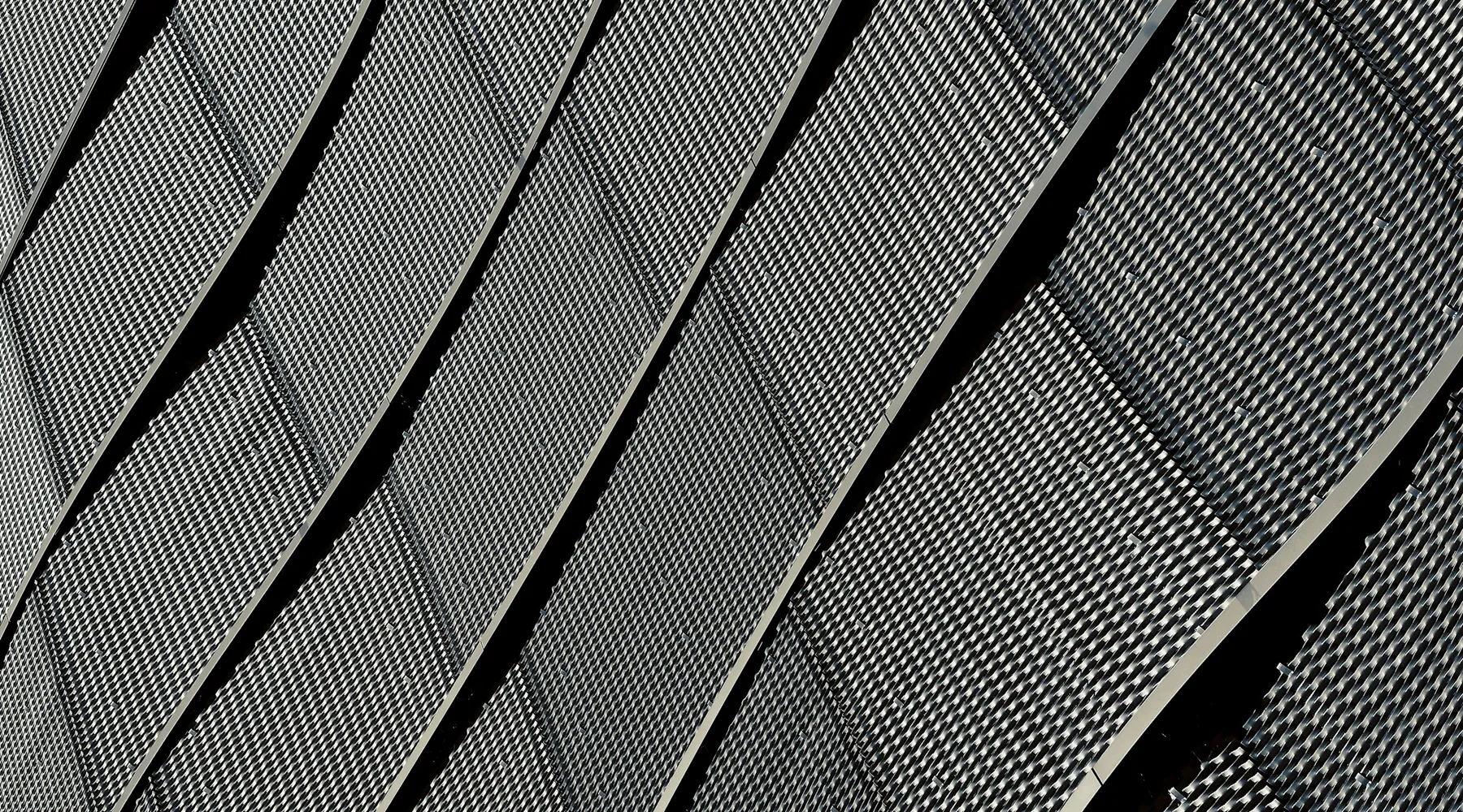 Close view of curved perforated metal facade panels with staggered vertical joints